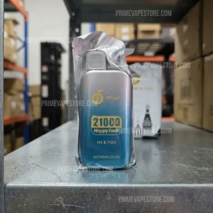 Disposable vape device with gradient blue-to-silver body, wrapped in plastic, labeled '210°C Watermelon Ice' on a warehouse shelf.
